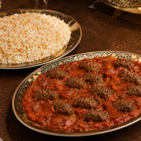 وجبة كباب هندي سوري بقطع اللحم المطهية مع الطماطم، تقدم في طبق فاخر مع طبق منفصل من الأرز بالشعيرية من دون مكسرات.