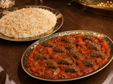وجبة كباب هندي سوري بقطع اللحم المطهية مع الطماطم، تقدم في طبق مع طبق منفصل من الأرز بالشعيرية من دون مكسرات.