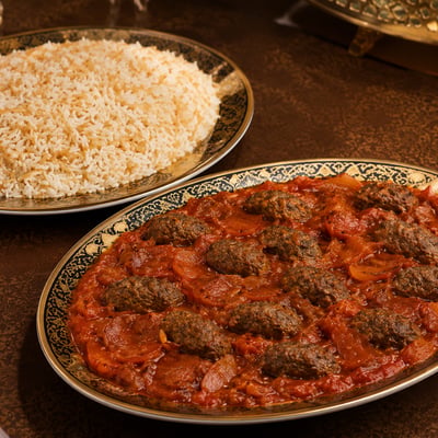 وجبة كباب هندي سوري بقطع اللحم المطهية مع الطماطم، تقدم في طبق فاخر مع طبق منفصل من الأرز بالشعيرية من دون مكسرات.
