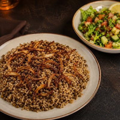 طبق مجدرة سورية بالعدس والأرز ومزين بالبصل المقلي، يقدم مع صحن سلطة خضراء طازجة.