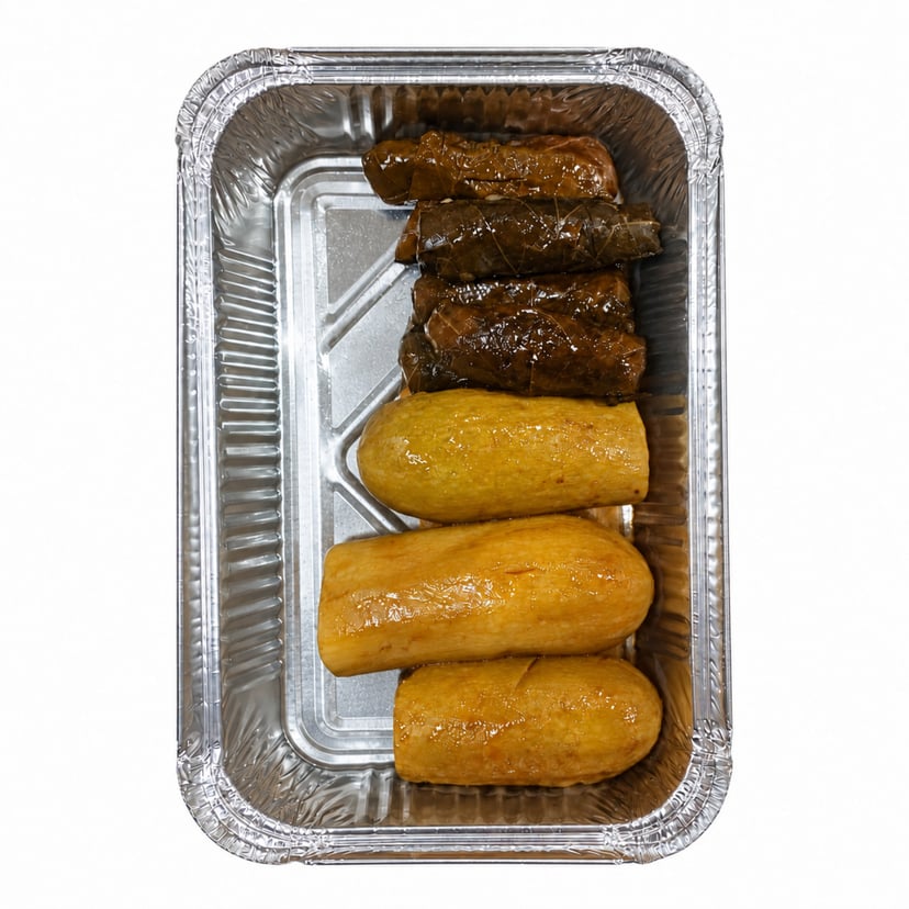 ست حبات محشي ورق عنب وثلاث حبات محشي كوسا في صينية ألمنيوم بخلفية بيضاء.